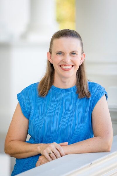 Rebecca Turk. White woman with shoulder length brown hair wearing a blue blouse.